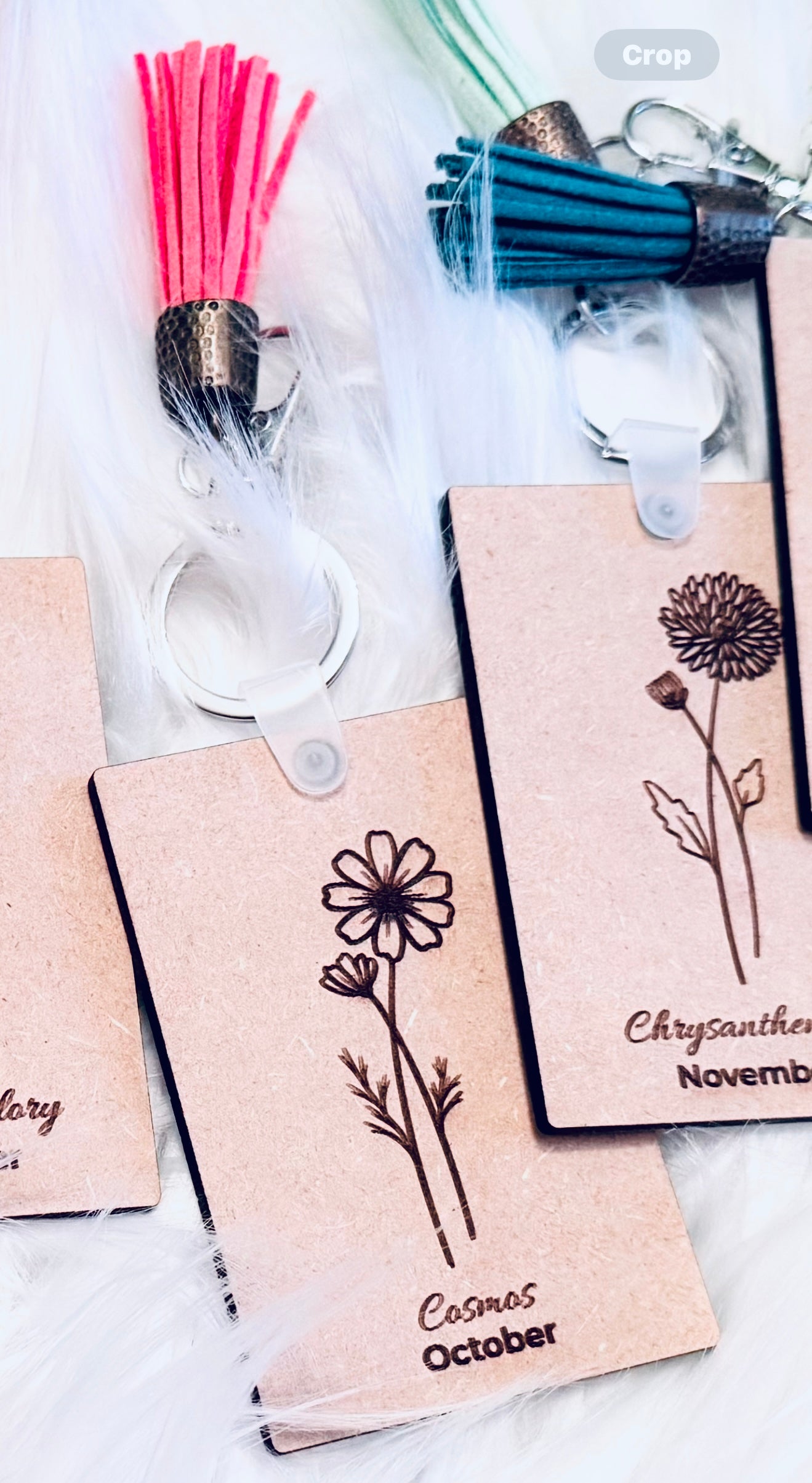 A collection of personalized birth flower keychains with different colored tassels and engraved floral designs, representing different months.