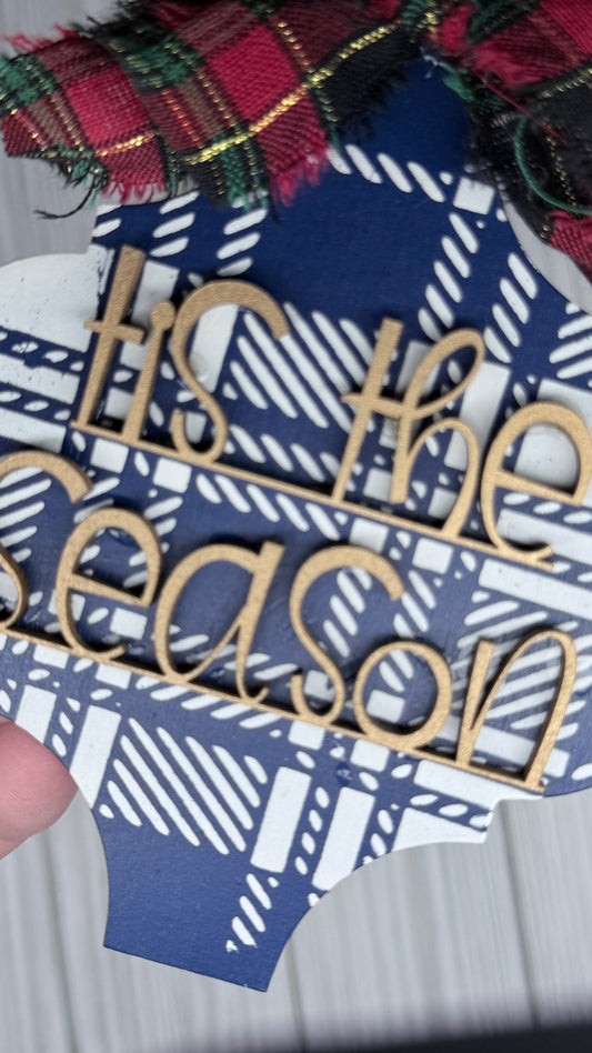 Blue and cream plaid background with gold 3D letters that read, "tis the season" and a fabric bow.