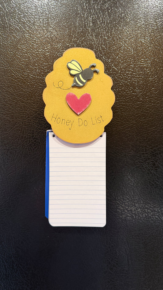 Close-up of Honey Do List magnetic clip holding spiral notebook - bee hive kitchen organizer detail"