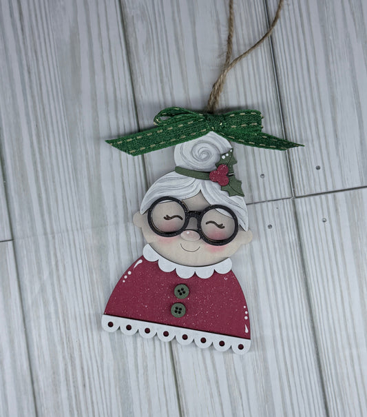 Decorative ornament shaped like a character with glasses and a green bow on a wooden surface