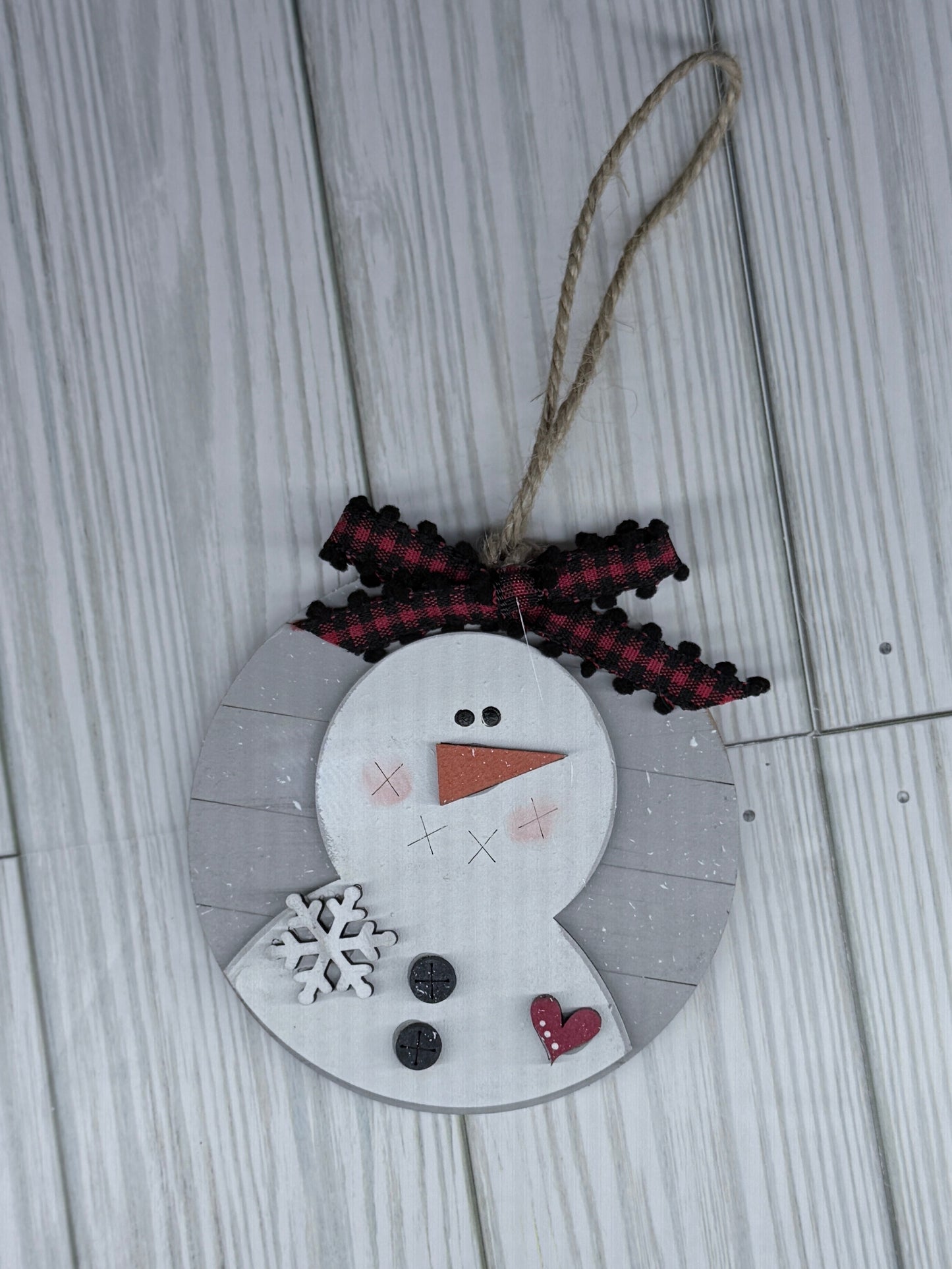 Decorative snowman ornament with a string on a wooden surface