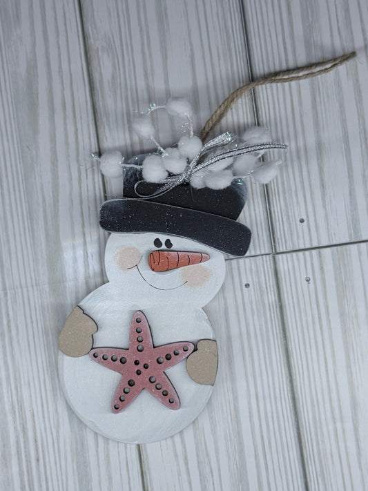 Decorative snowman ornament with a starfish on a wooden surface