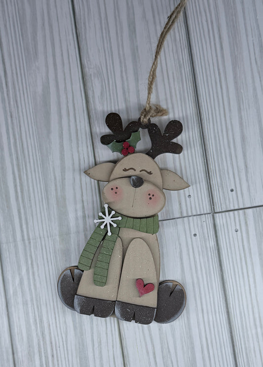 Decorative reindeer ornament with a green scarf on a wooden surface background