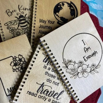 "Collection of personalized wooden journals with various custom engraving designs and text options"