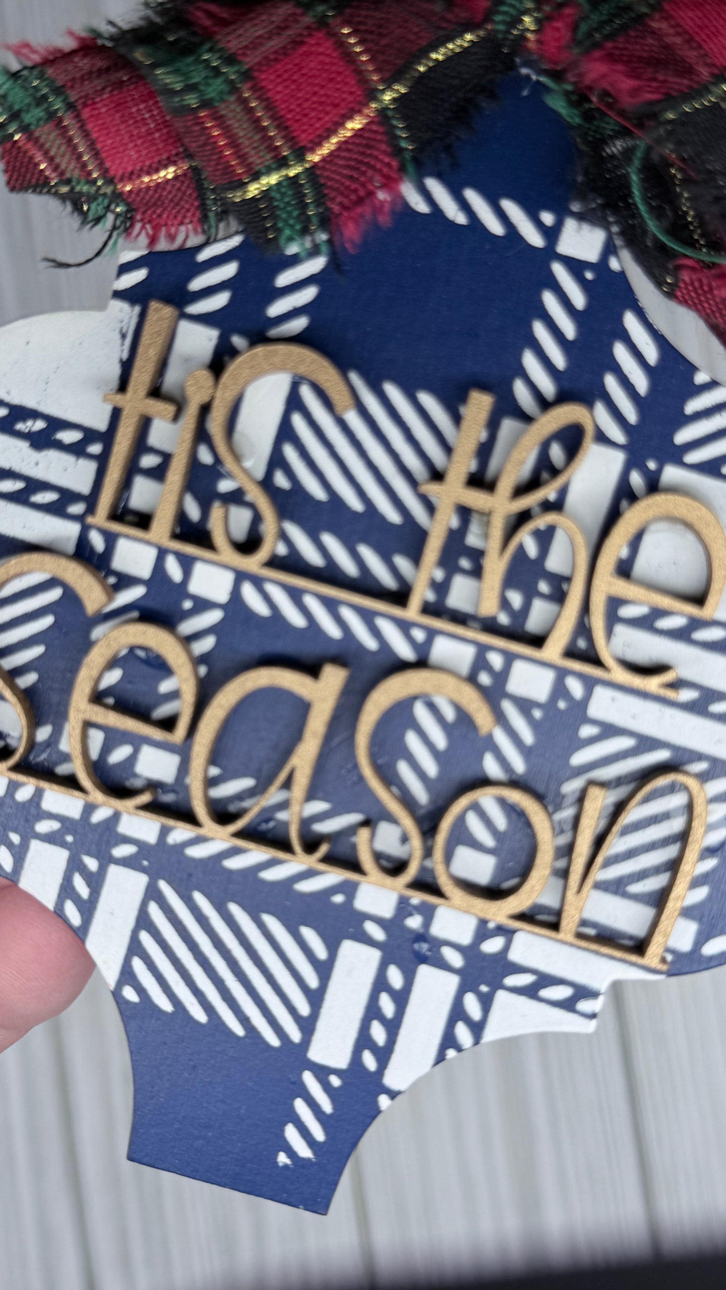 Blue and cream plaid background with gold 3D letters that read, "tis the season" and a fabric bow.  