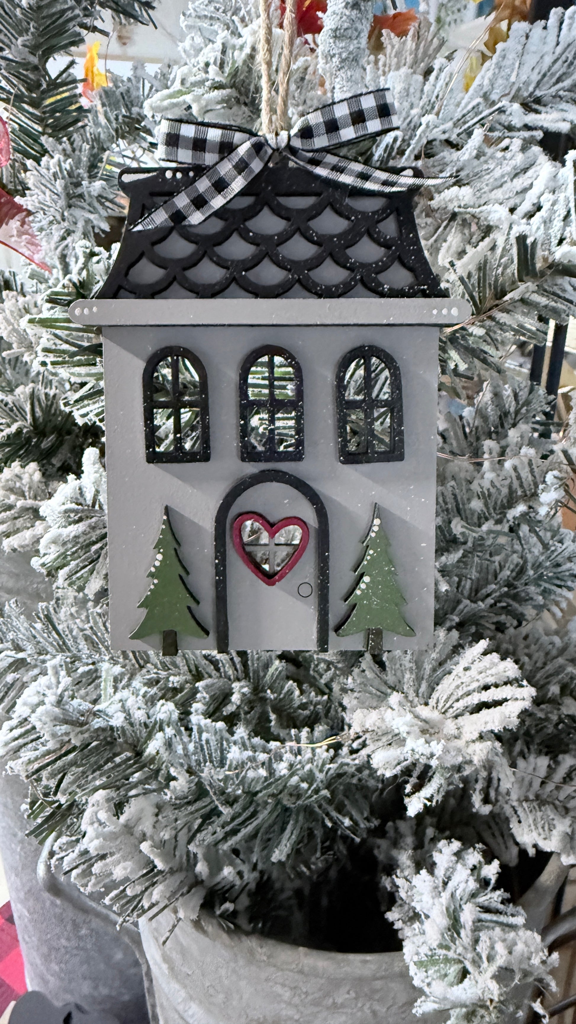 Decorative house ornament with a heart on a Christmas tree