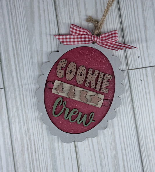 Decorative sign with 'Cookie Crew' text on a wooden surface