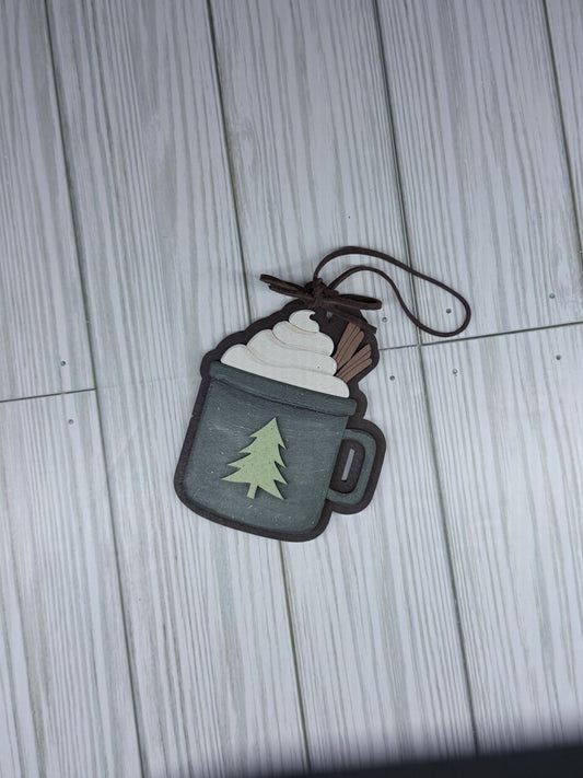 Mug ornament with a  tree on the mug. leather bow and hanger on reustic surface. 