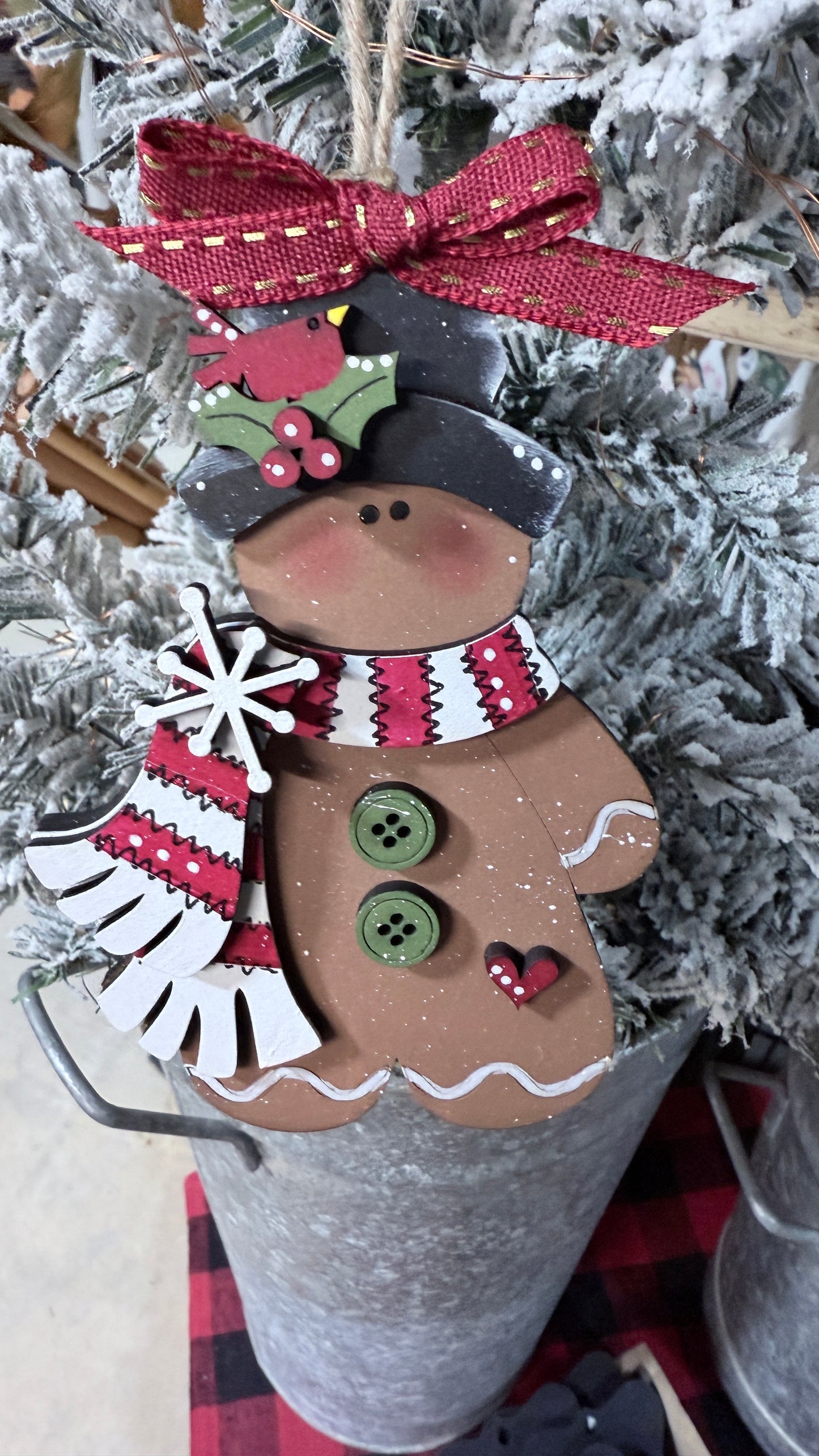 Decorative gingerbread man ornament with a red bow on a Christmas tree.