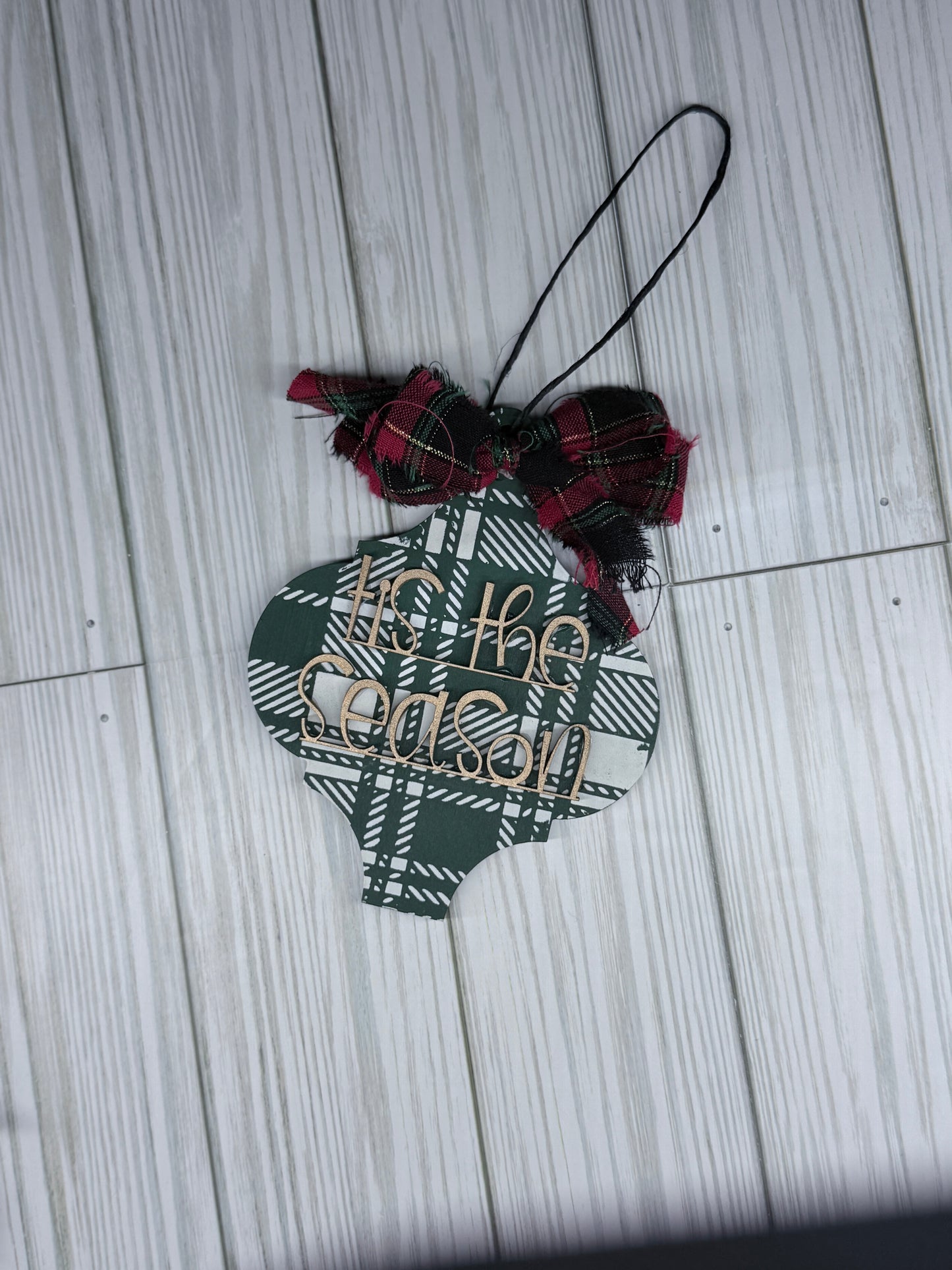 Decorative ornament with plaid pattern and text on a wooden surface