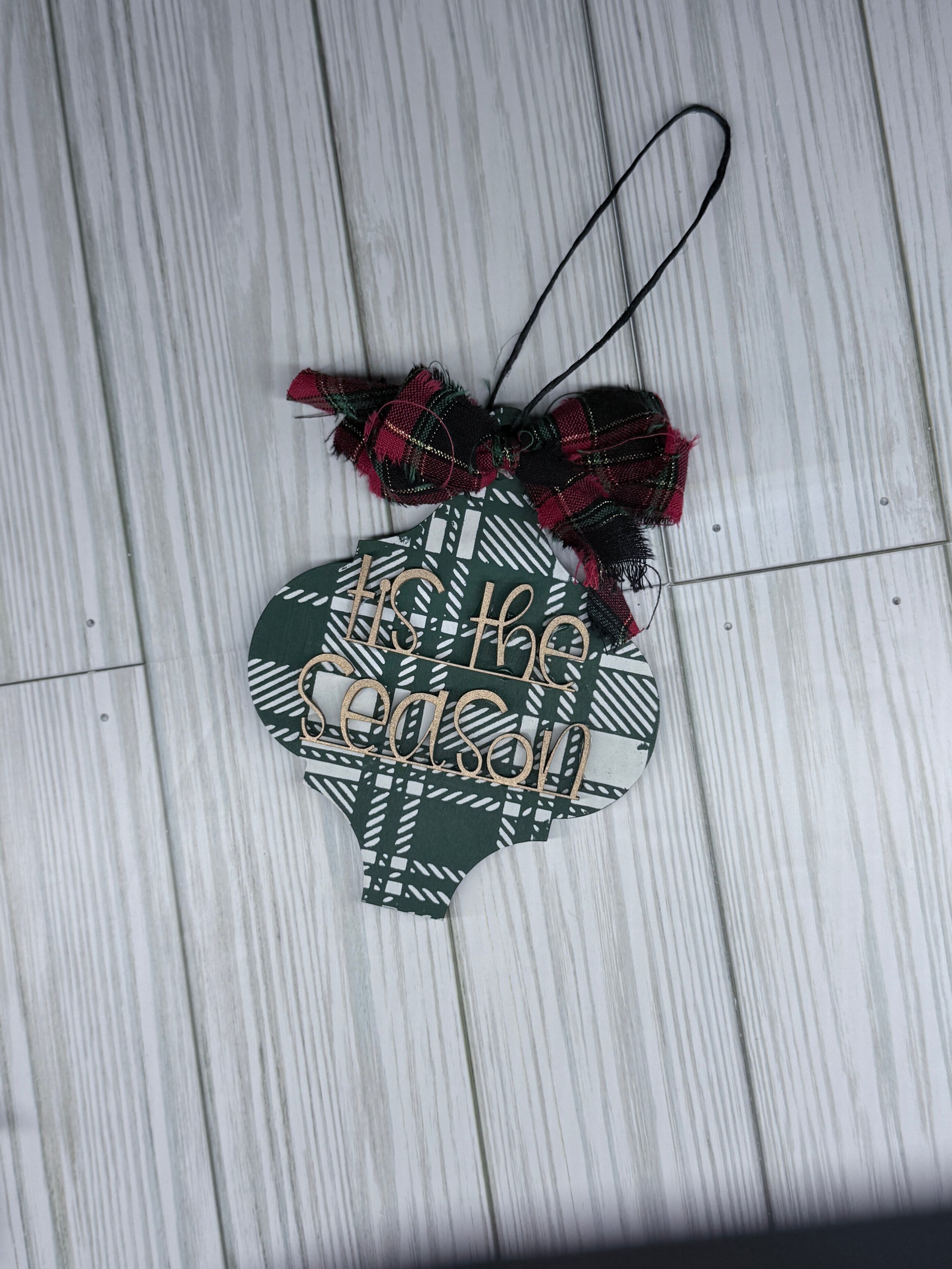 Decorative ornament with plaid pattern and text on a wooden surface