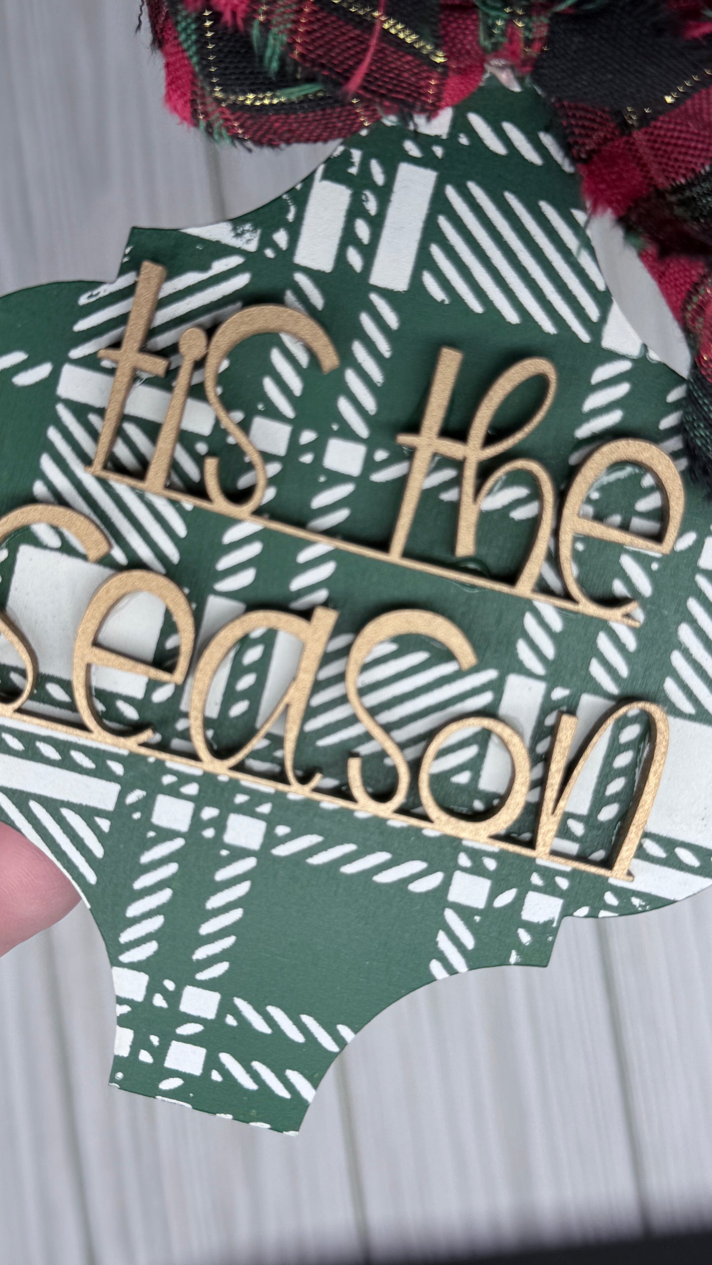 Green and ivory plaid background with gold 3D letters that read, Tis the Season and a fabric bow 