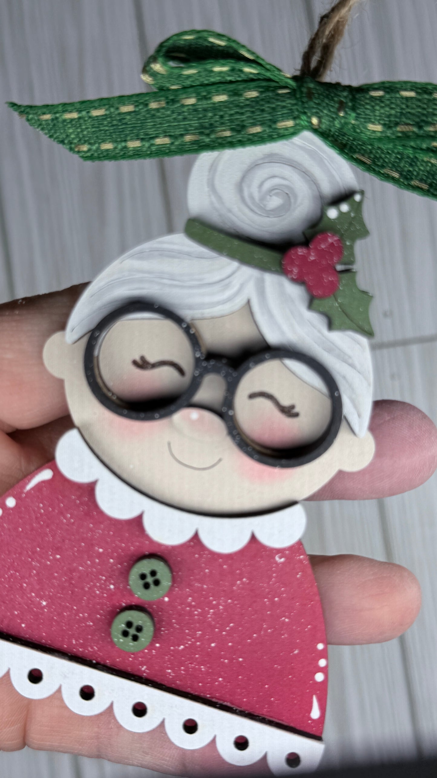 Mrs. Clause Tree ornament features a green ribbon, green buttons on a red dress and black glasses.  