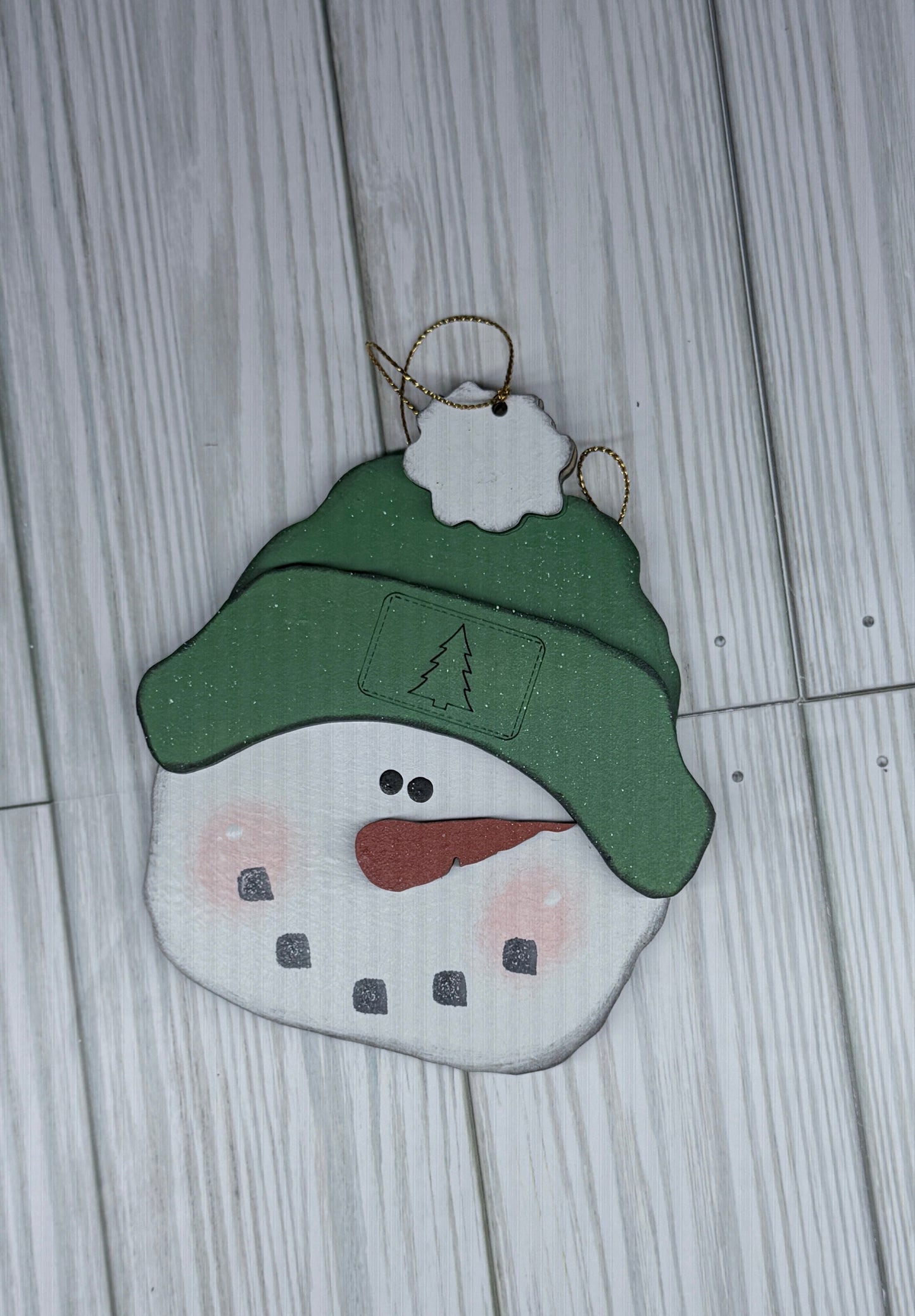 Decorative snowman ornament with a green hat on a wooden surface