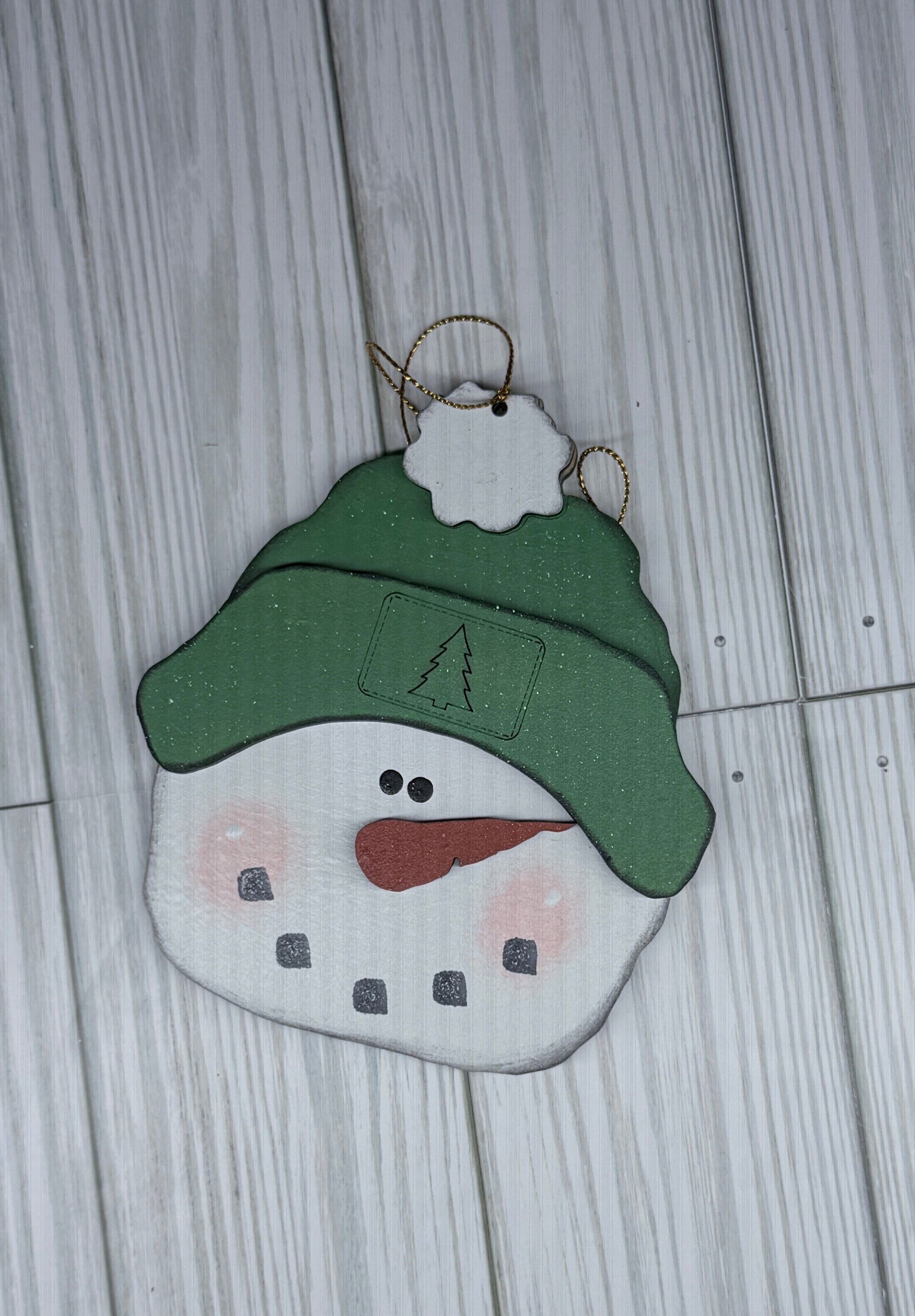 Decorative snowman ornament with a green hat on a wooden surface