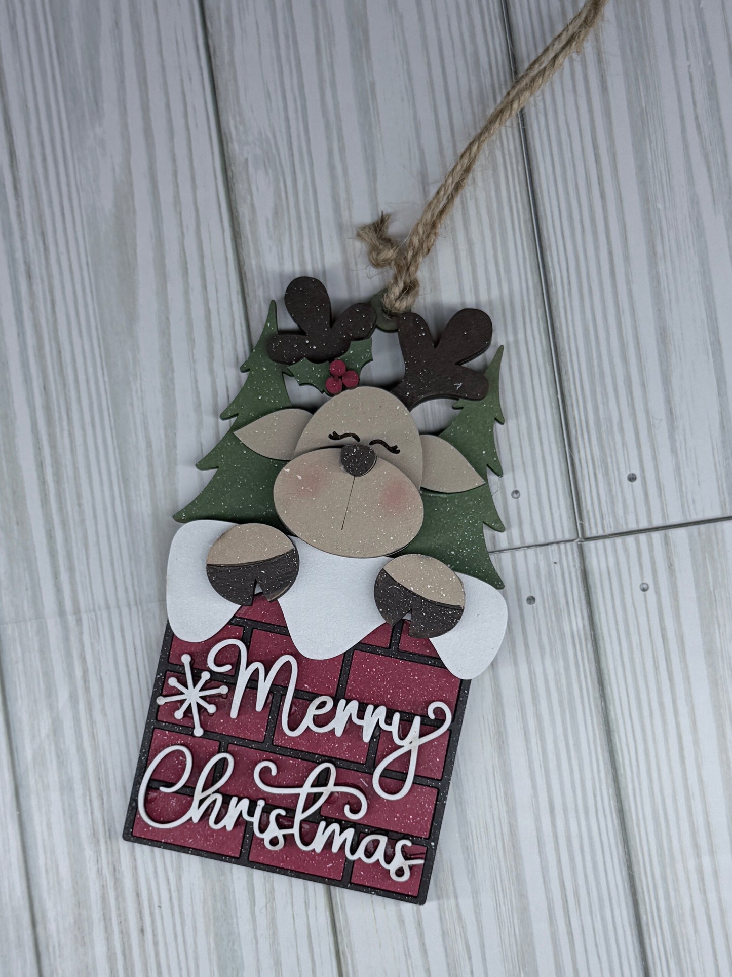 Christmas-themed wooden ornament with a reindeer design and 'Merry Christmas' text on a light wooden surface.