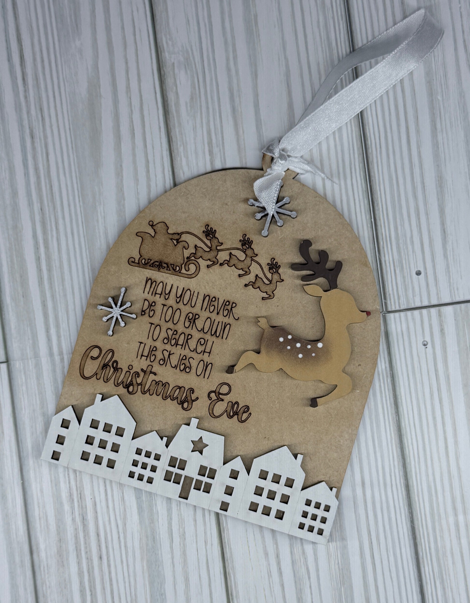 Decorative ornament of Santa flying over the homes as his reindeer lead the way.   "May you never be too grown up to search the skies on Christmas Eve" engraved.  