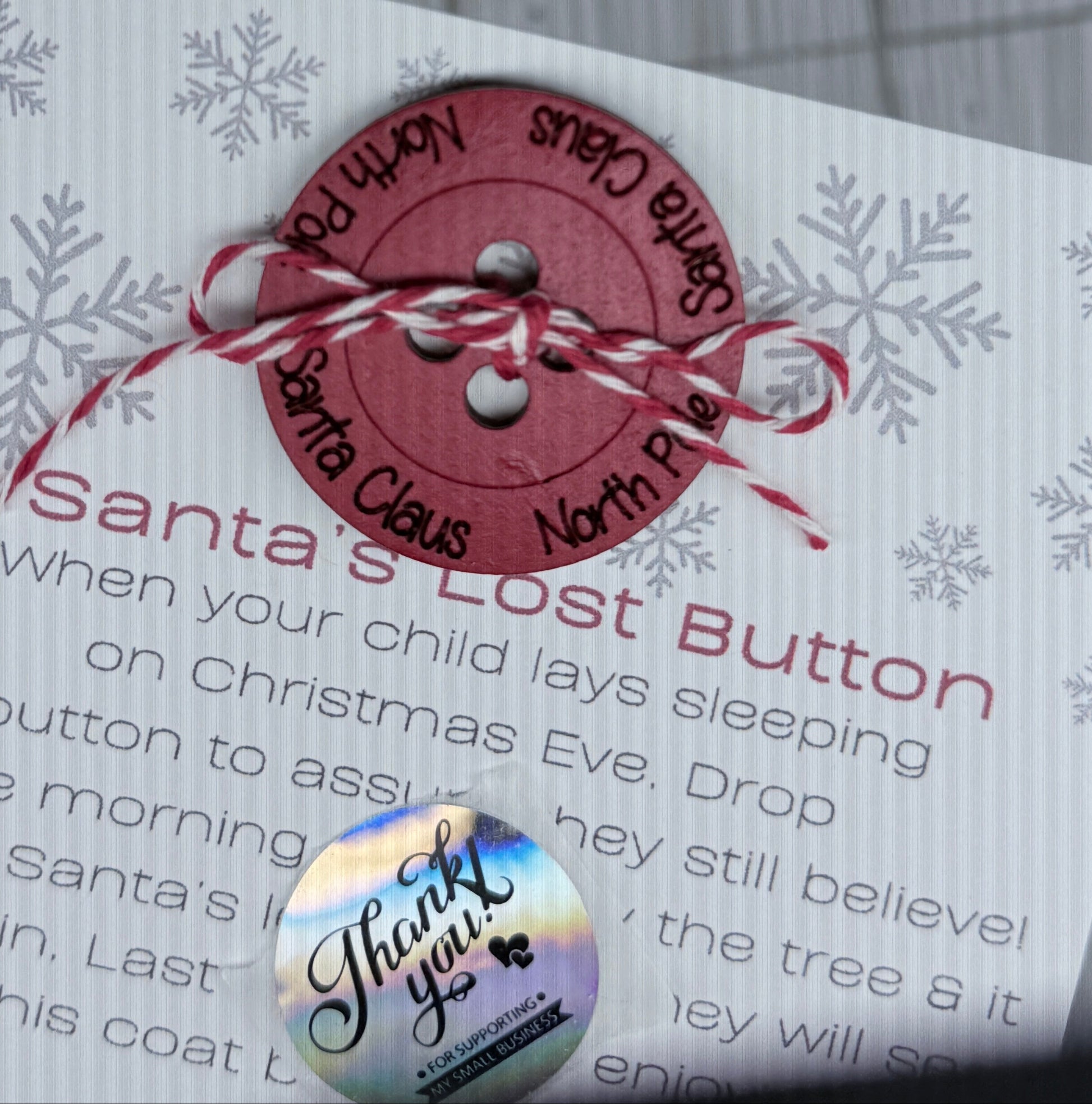Button labeled 'Santa's Lost Button' on a card with text and tied with thread as if it popped off Santa's coat while leaving presents. 