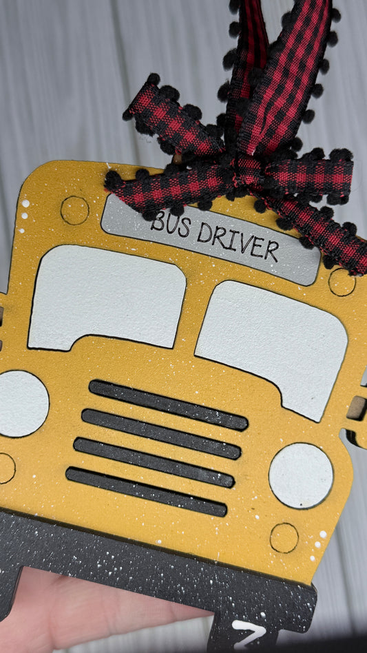 School bus ornament with 'Bus Driver' text on top sign and a red and black checkered bow hanger. 