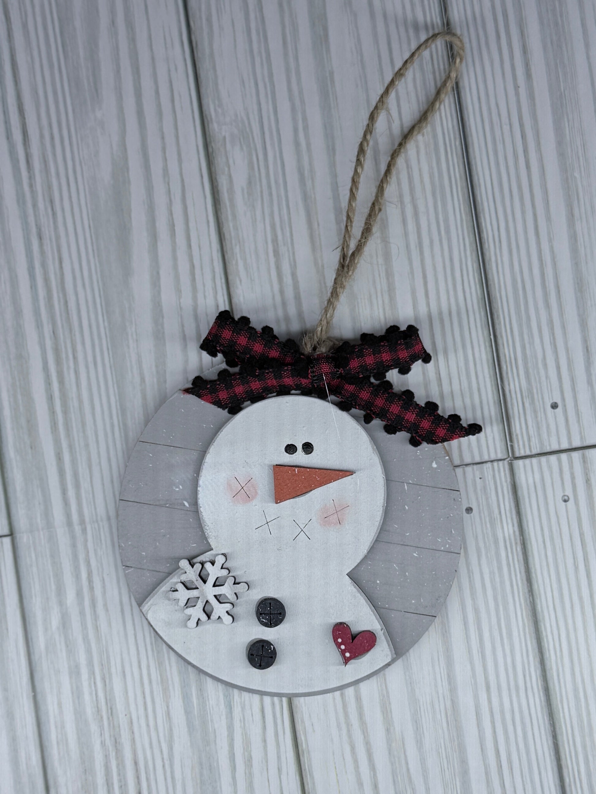 Decorative snowman ornament with a string on a wooden surface