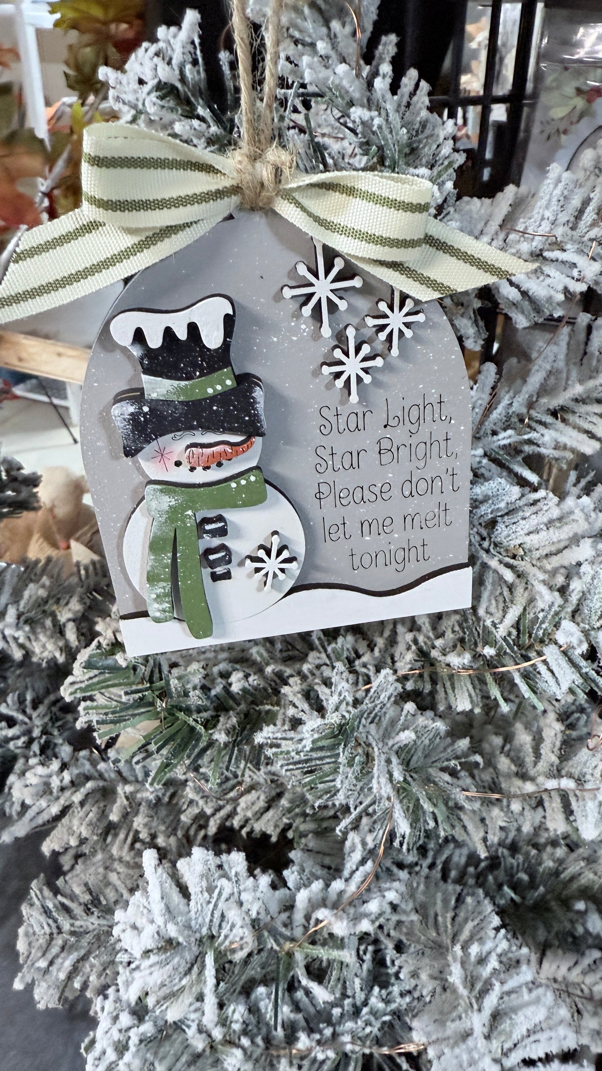 Decorative snowman ornament with a message on a Christmas tree.