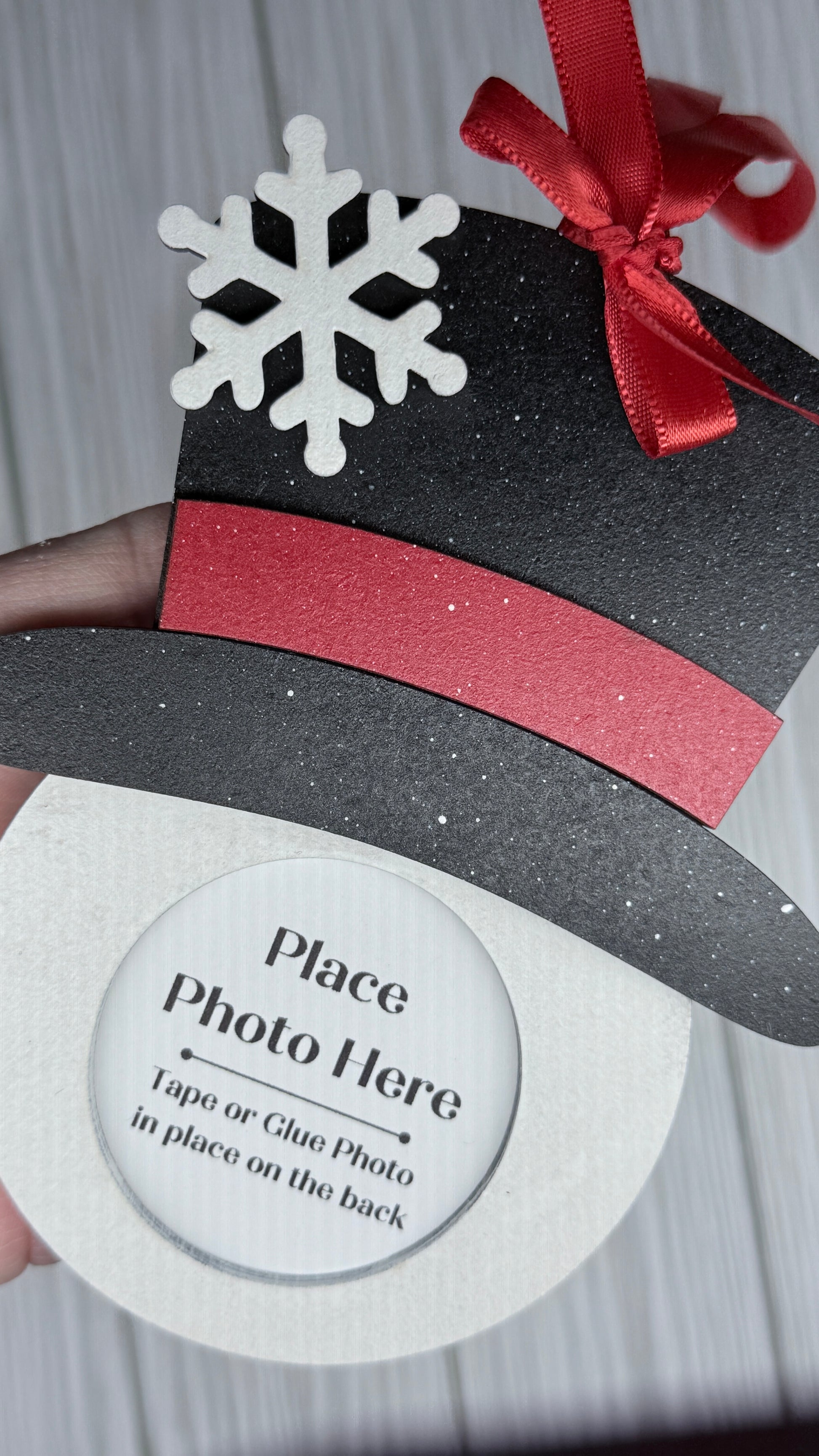 Snowman face photo holder for the tree.  Black top hat, red brim, and a white face.  Adorn with a red satin ribbon bow and hanger.  3D snowflake on the hat.  