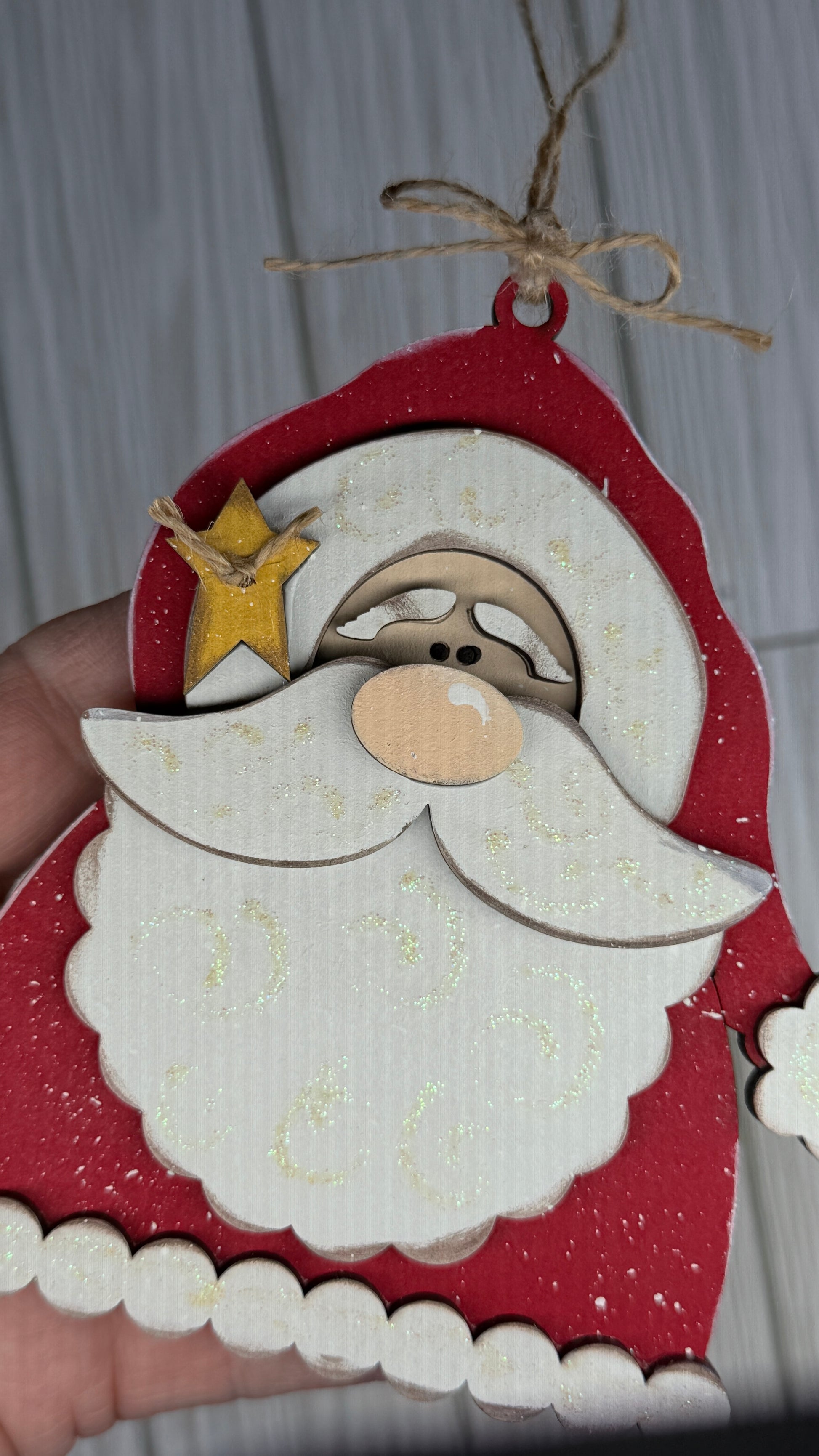 Wooden Santa Claus ornament with a star on his hat, twine hanger, shown on white background