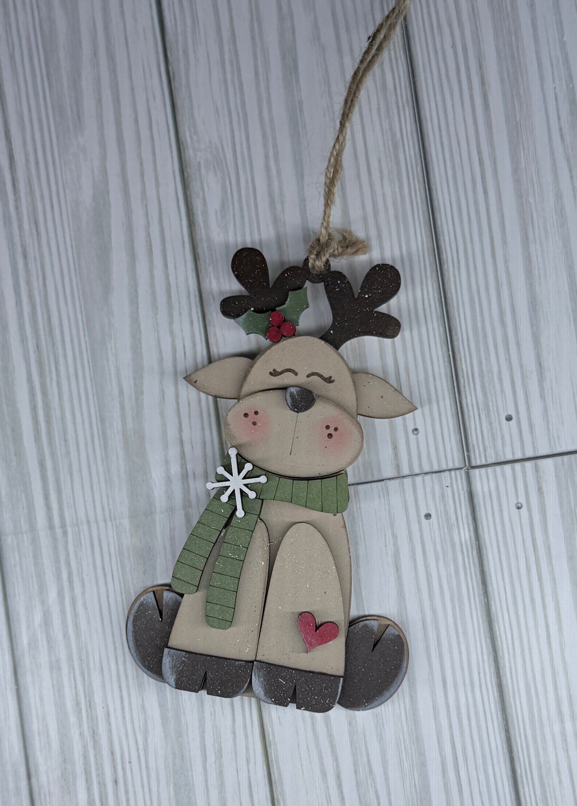 Decorative reindeer ornament with a green scarf on a wooden surface background